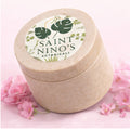 Saint Nino’s Botanicals body butter jar in speckled beige container displayed on pink background with soft floral accents