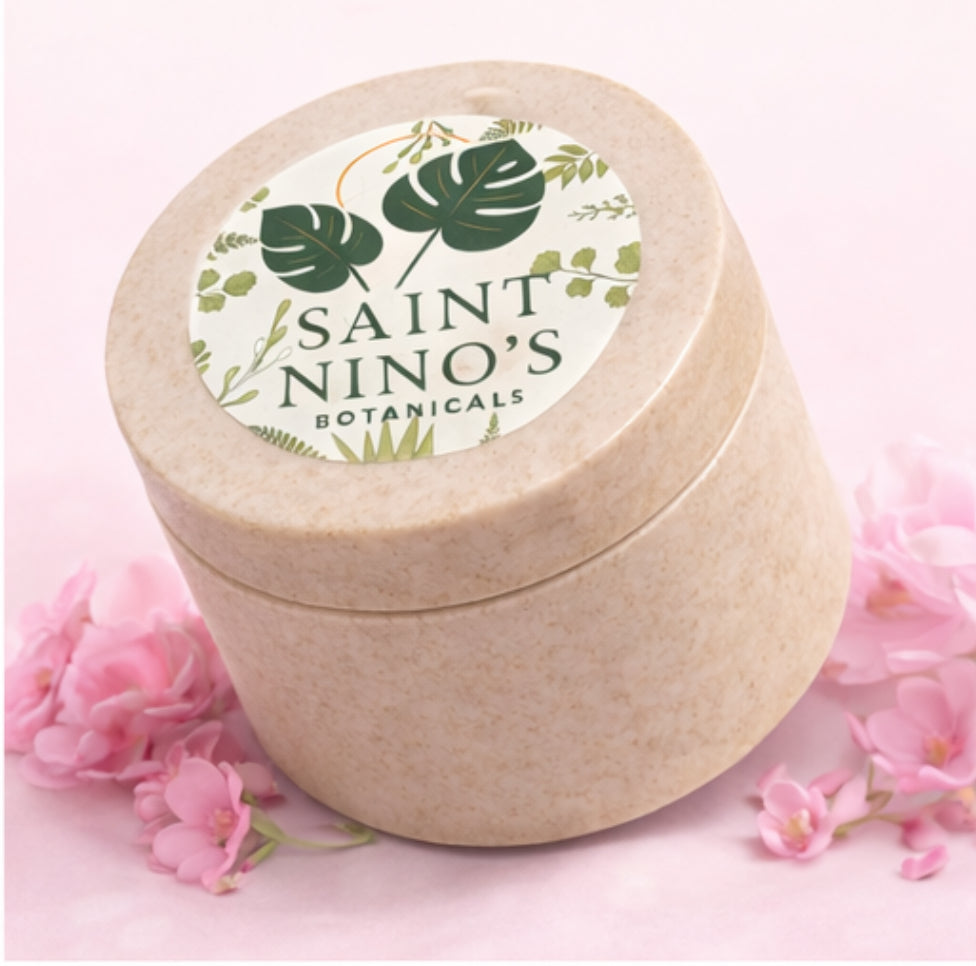 Saint Nino’s Botanicals body butter jar in speckled beige container displayed on pink background with soft floral accents