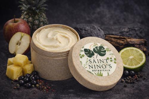 Two containers of cream with 'Saint Nino's Botanicals' branding on a dark background with fruits and spices.