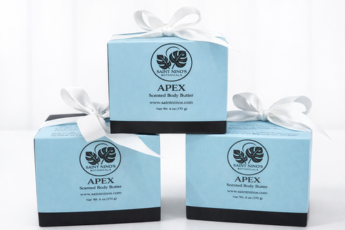 Three boxes of Saint Ninian's Apex scented body butter with white ribbons on a white background.