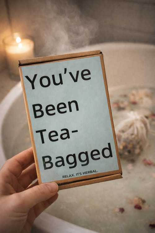 Hand holding a box that reads 'You've Been Tea-Bagged' in a bathroom setting. With a smal text below that reads relax its herbal .